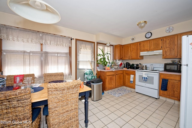kitchen with light countertops, under cabinet range hood, and white appliances