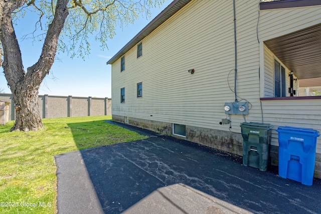 view of home's exterior with a lawn and fence