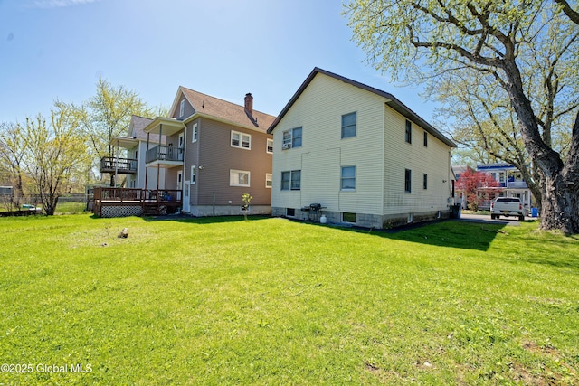rear view of house with a lawn and a balcony