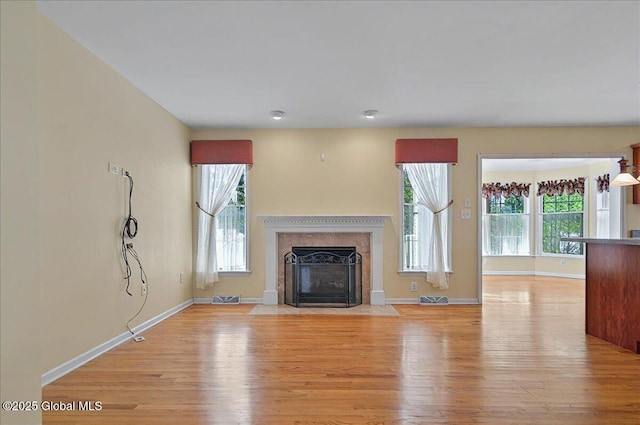 unfurnished living room with baseboards, visible vents, light wood-style flooring, and a fireplace