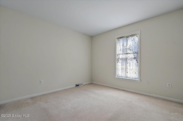 spare room with visible vents, baseboards, and light carpet