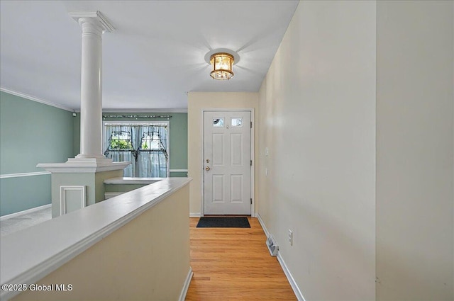 doorway to outside with ornate columns, baseboards, and light wood finished floors