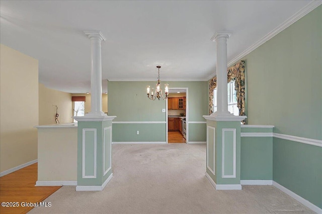 empty room featuring a healthy amount of sunlight, baseboards, decorative columns, and a notable chandelier