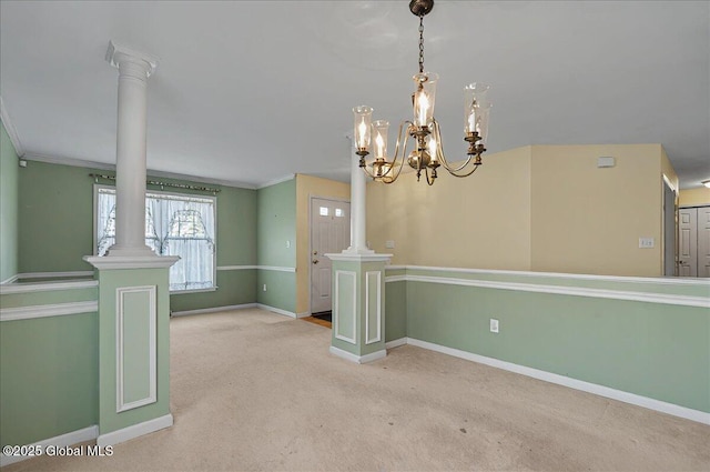 spare room featuring crown molding, baseboards, ornate columns, and carpet floors