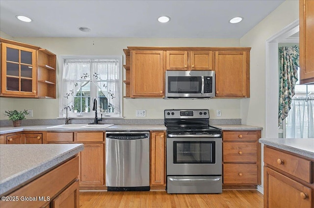 kitchen featuring light countertops, open shelves, a sink, and stainless steel appliances