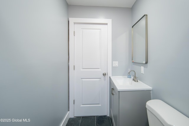 half bathroom featuring vanity, baseboards, and toilet