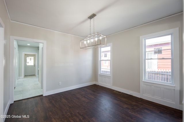 empty room featuring dark wood-style flooring, baseboards, a chandelier, and visible vents