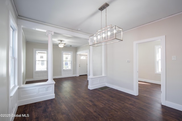 unfurnished dining area featuring ornate columns, ornamental molding, and dark wood-type flooring