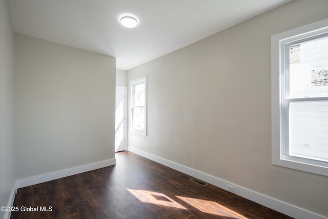 spare room featuring baseboards, visible vents, and dark wood-type flooring