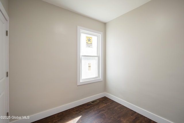 empty room with baseboards, visible vents, a wealth of natural light, and dark wood-style floors
