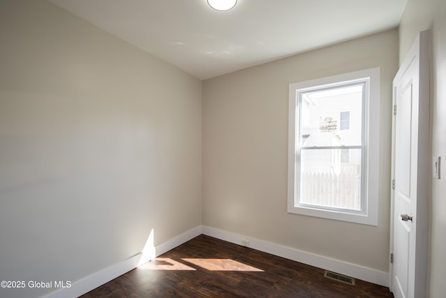spare room with baseboards, visible vents, and dark wood-style floors