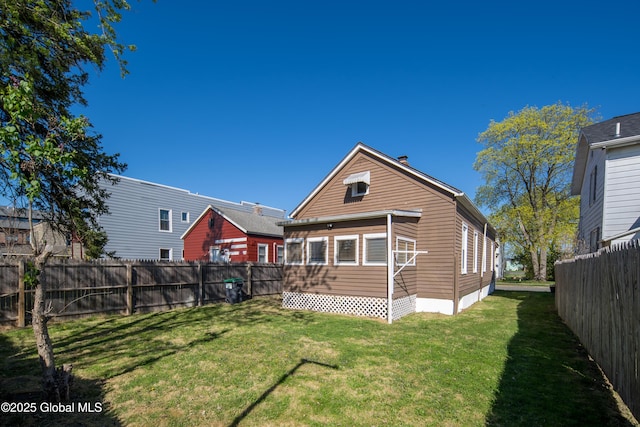 back of property with a lawn, a fenced backyard, and crawl space