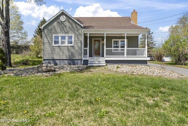 view of front of house featuring a chimney, a porch, and a front lawn