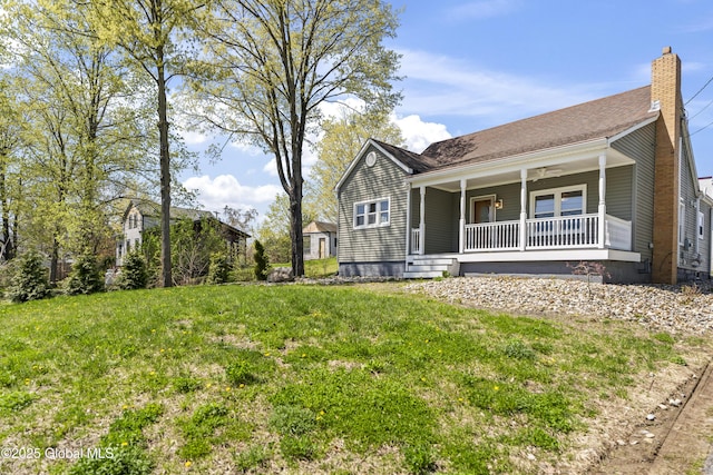 view of front facade featuring covered porch, a chimney, and a front lawn