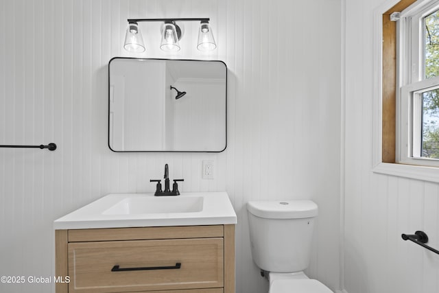 bathroom with vanity, wooden walls, a wealth of natural light, and toilet