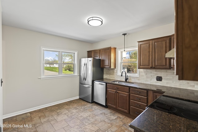 kitchen with appliances with stainless steel finishes, a sink, plenty of natural light, baseboards, and tasteful backsplash