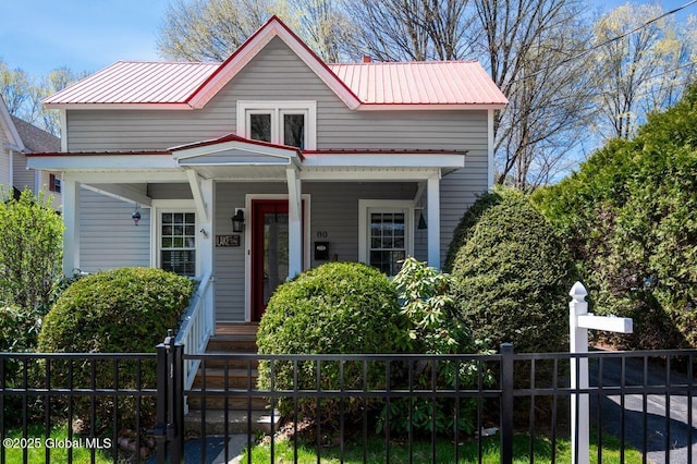 bungalow featuring fence, covered porch, and metal roof