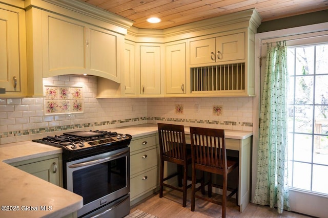 kitchen with light wood-style floors, light countertops, stainless steel gas stove, decorative backsplash, and wooden ceiling