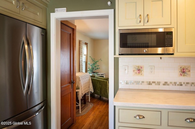 kitchen featuring appliances with stainless steel finishes, tasteful backsplash, dark wood-style flooring, and cream cabinetry