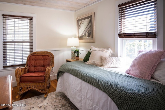 bedroom featuring wood ceiling, wainscoting, and wood finished floors
