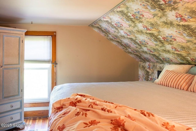 bedroom with multiple windows, vaulted ceiling, and wood finished floors