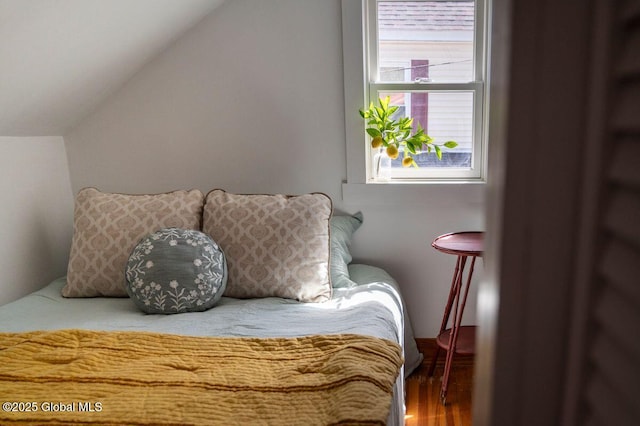 bedroom with wood finished floors and lofted ceiling