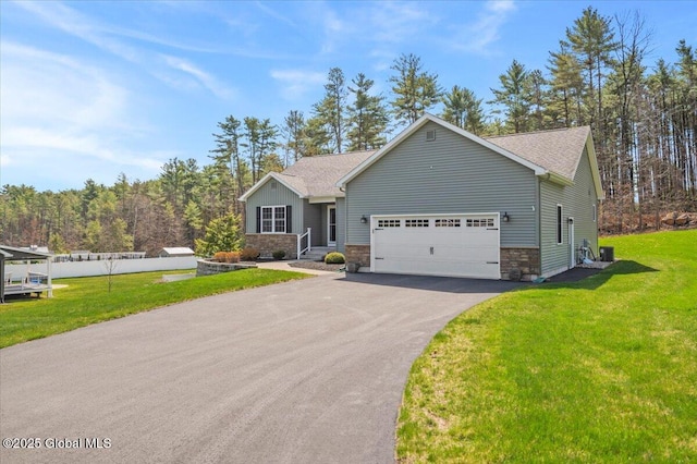 single story home with an attached garage, a front lawn, driveway, and stone siding