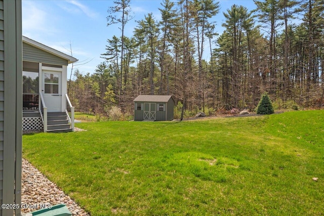 view of yard featuring a storage unit, an outdoor structure, and a wooded view