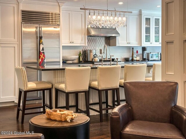 5A6 Sagamore Rd, Bolton, NY 12814 - kitchen with dark countertops, a breakfast bar, white cabinetry, under cabinet range hood, and dark wood-style floors