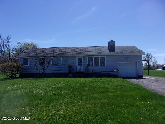 ranch-style house with an attached garage, a chimney, a front lawn, and aphalt driveway