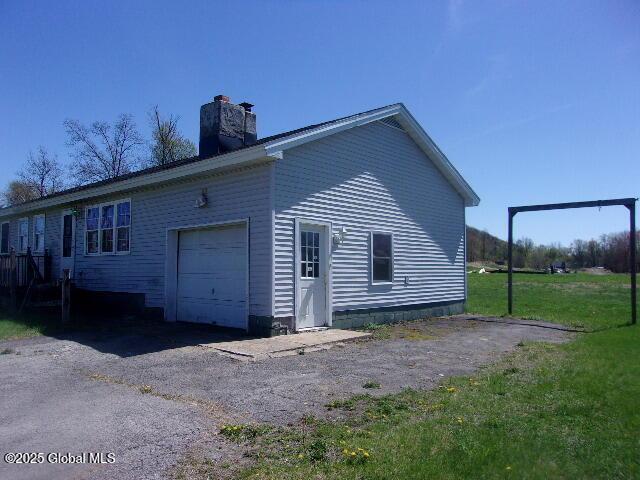 view of home's exterior with an attached garage and a chimney