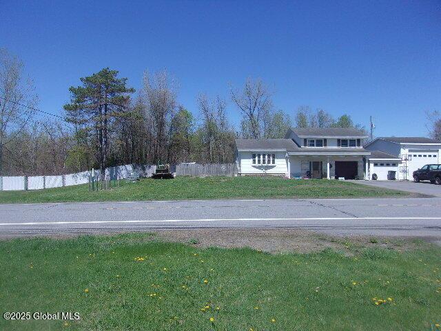 view of front facade featuring fence, a garage, driveway, and a front yard