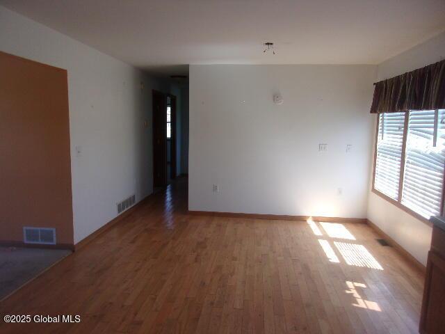 spare room featuring baseboards, visible vents, and light wood finished floors