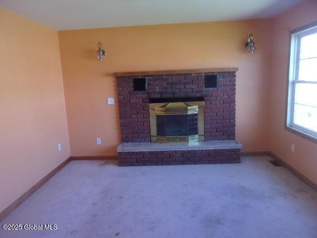 unfurnished living room with baseboards, a wealth of natural light, carpet, and a fireplace