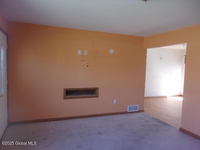 unfurnished room featuring visible vents, carpet, and baseboards
