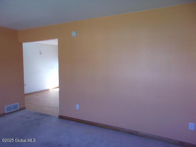 carpeted empty room featuring baseboards and visible vents