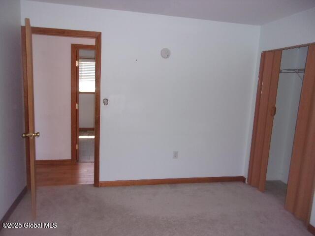 unfurnished bedroom with a closet, carpet, and baseboards