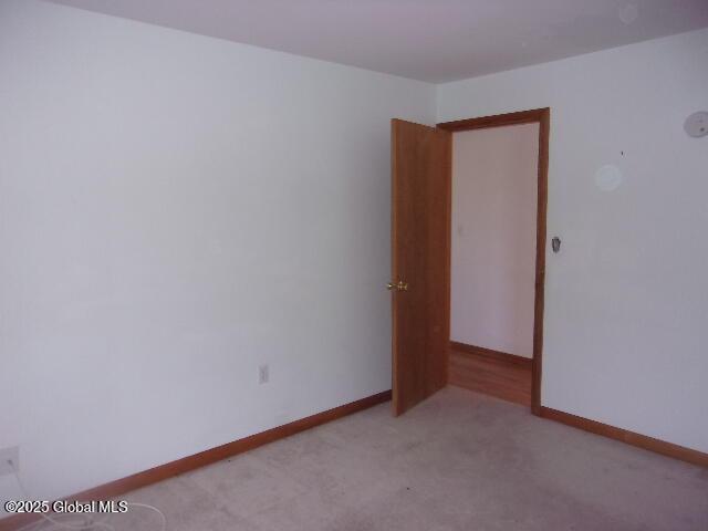 spare room with baseboards and carpet