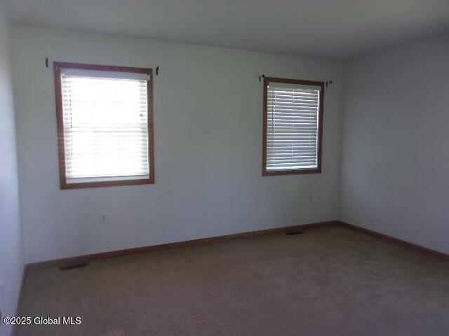 carpeted spare room featuring baseboards