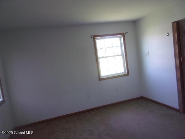 unfurnished room with baseboards and carpet