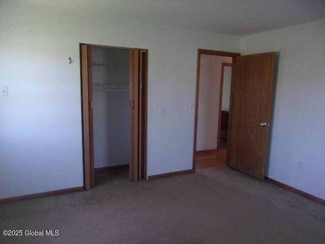 unfurnished bedroom featuring baseboards, carpet, and a closet