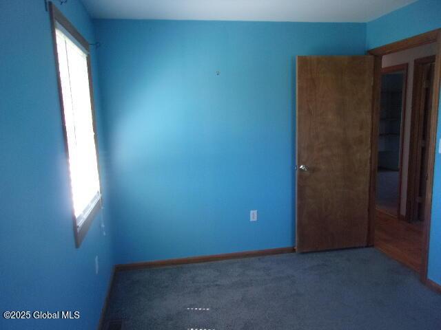 carpeted empty room featuring baseboards