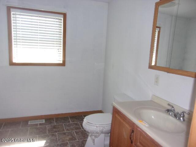 bathroom with toilet, baseboards, and vanity
