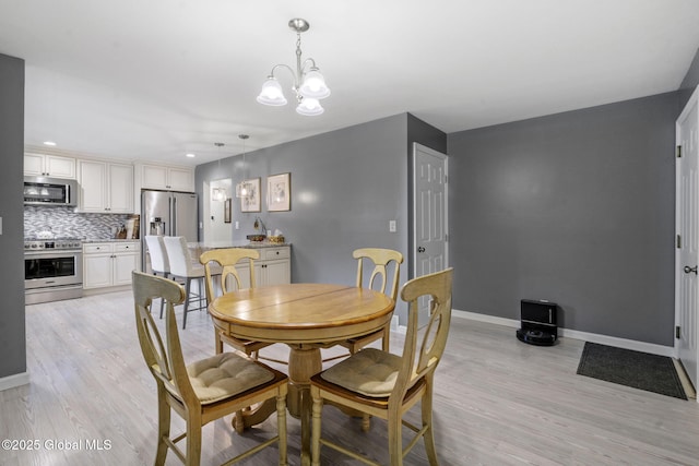 dining area featuring light wood finished floors, baseboards, and a chandelier