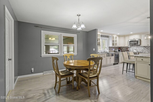 dining space with light wood finished floors, a chandelier, baseboards, and recessed lighting