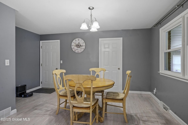 dining area with light wood-style flooring, a chandelier, and baseboards