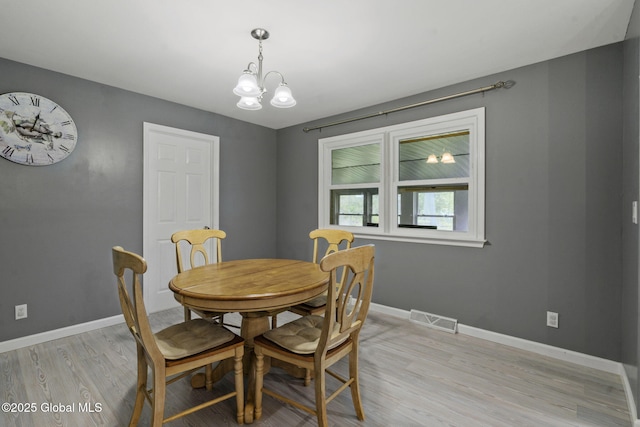 dining space featuring light wood-style floors, a chandelier, and baseboards
