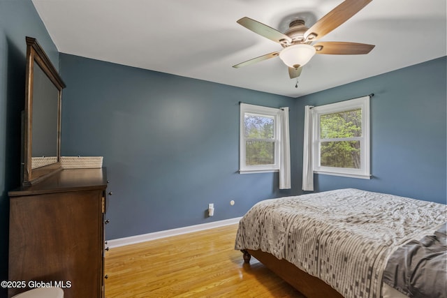 bedroom with light wood-type flooring, baseboards, and ceiling fan