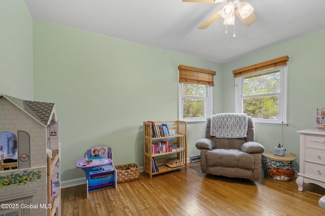 game room with wood finished floors, ceiling fan, baseboard heating, and baseboards