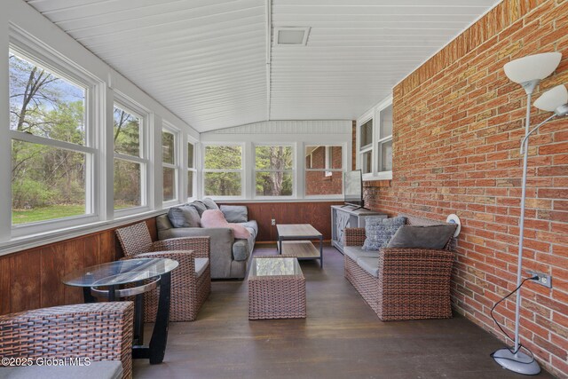 sunroom featuring healthy amount of natural light, outdoor lounge area, and lofted ceiling
